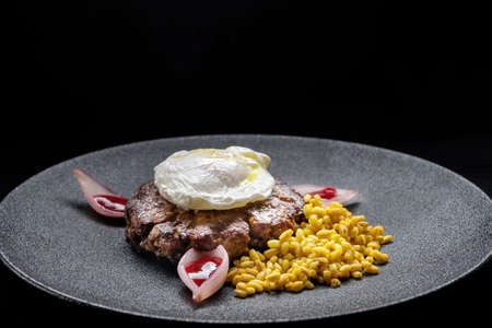 Fried venison steak with poached egg and boiled barley.の写真素材