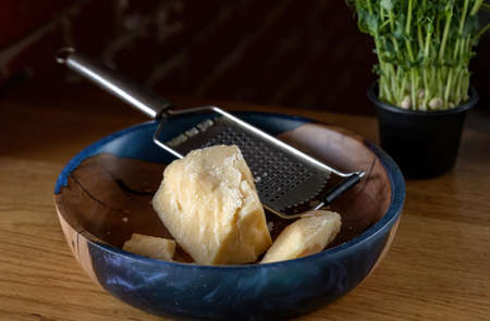 Parmesan cheese with a grater. Shallow depth of field. Beautiful wooden plate.の写真素材