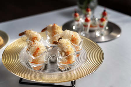 Shrimps wrapped in wheat thread and baked. Catering, beautiful table. Silver designer plate.の写真素材