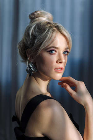 Close up studio portrait of a pretty blonde woman in black top, looking at the camera.の写真素材