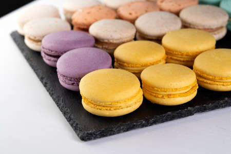 Macarons are laid out on a black slate in beautifully colored rows.の写真素材