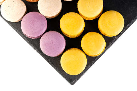 Macarons are laid out on a black slate in beautifully colored rows.の写真素材
