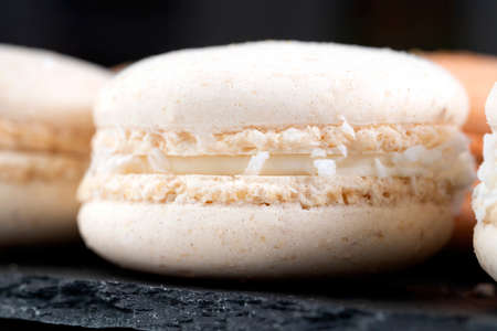 Macarons are laid out on a black slate. Filling with delicate cream and coconut flakes.の写真素材