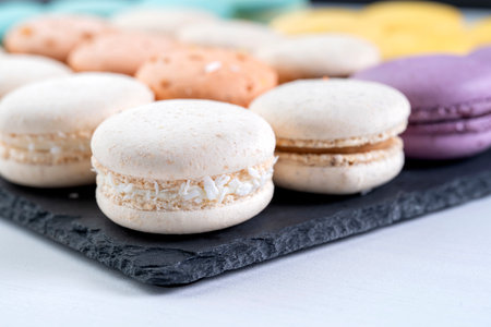 Macarons are laid out on a black slate in beautifully colored rows.の写真素材