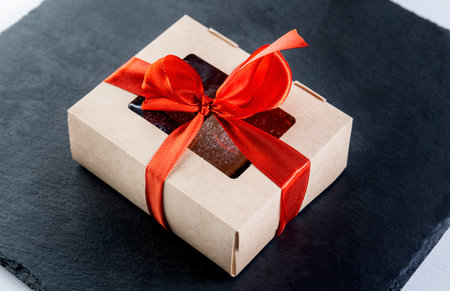 Christmas gift in a paper box on a black slate tied with a red ribbon.の写真素材