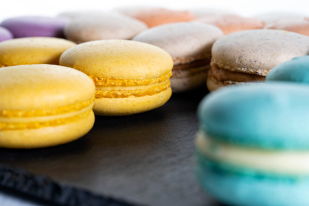 Macarons are laid out on a black slate in beautifully colored rows-2.の写真素材
