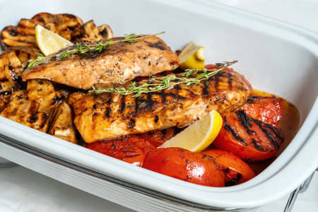 Salmon pieces, champignons, grilled tomatoes in marmite.の写真素材