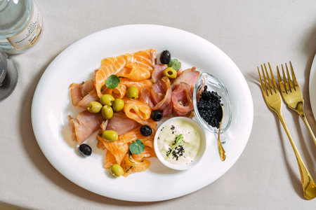 Seafood platter with salmon slice, black caviar, decorated with olive on white plate.の写真素材