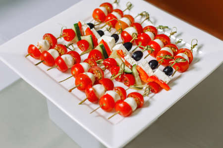 Cheese and olive canapes with tomato and cucumber. Also a quail egg.の写真素材