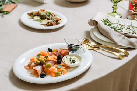 Seafood platter with salmon slice, black caviar, decorated with olive on white plate.の写真素材