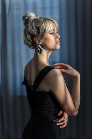 Close up studio portrait of a pretty blonde woman in black top, looking at the camera.の写真素材
