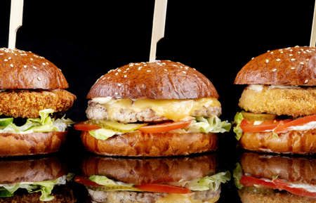 Delicious hamburgers served on black background. Burgers with different fillings, fish chicken, chickpeas.の写真素材