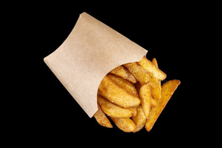 Fried potato wedges spilled out of a paper bag.の写真素材