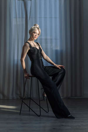 Close up studio portrait of a pretty blonde woman in black top and black pants.の写真素材