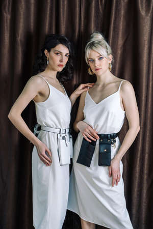 Sexy young blonde and brunette watching in the mirror. Leather jewelry and huge gold earrings. Young...