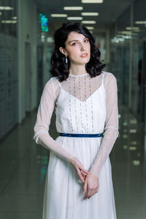 Brunette girl wearing white designer dress beautiful portrait. Beautiful and sensual, with a shopping center.の写真素材