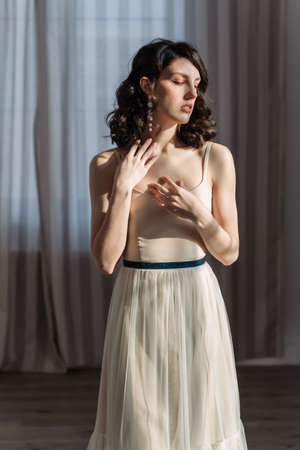 Cute young girl stands in the studio on the background of curtains.の写真素材