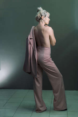 Sexy young blonde looking standing topless with a jacket in his hand. Full-length photoの写真素材