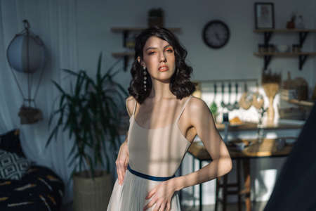 Cute young girl stands in the studio, beautiful apartment, all bathed in sunlight.の写真素材