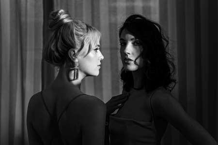 Studio portrait blondes and brunettes. Brunette watching at the camera, blonde closed her eyes.の写真素材