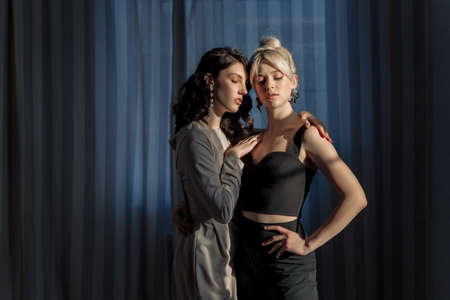 Studio portrait blondes and brunettes. One girl hugs another, beautiful sunlight falls on the faces.の写真素材
