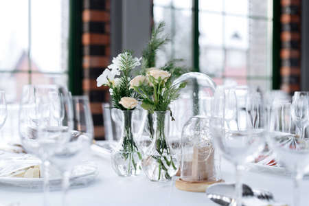 Beautifully served wedding table decorated with designer vases with bouquets.