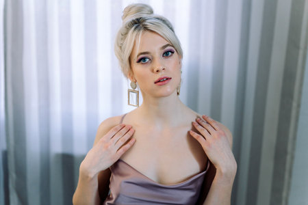 Studio portrait of blonde woman, young and tender. Horizontal photo, hip portrait. Direct gaze into the camera, hands on shoulders.の写真素材