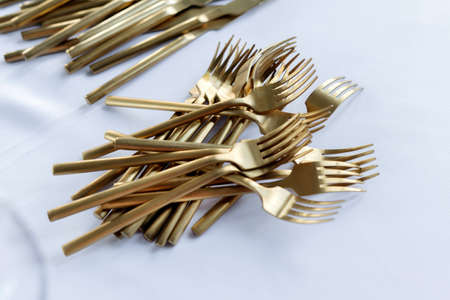 Vintage cutlery on an table covered with white tablecloth, copy space, horizontal. Focus on a bunch of forks.の写真素材