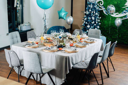 A beautiful Christmas table is set for a family dinner. Everything is decorated with balloons.の写真素材