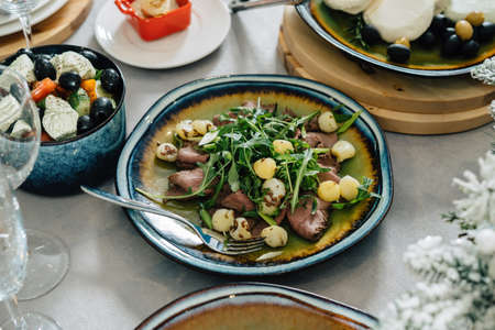 A dish with meat and young baked potatoes, decorated with salad. Nicely served table.の写真素材