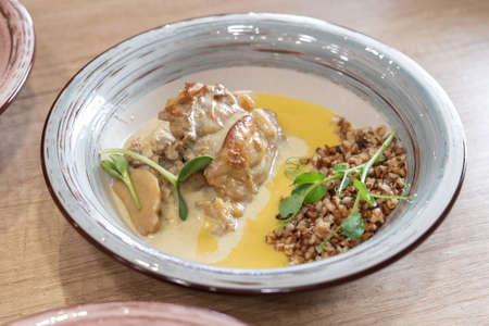 Buckwheat porridge with a chicken on a white plate. On a wooden table with gravy and herbs.の写真素材