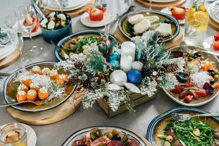 A beautiful Christmas table is set for a family dinner. Composition of twigs and cones in the middle of the table.の写真素材