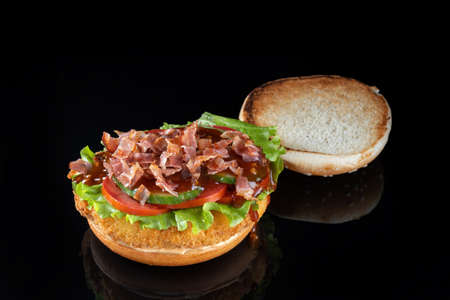 Bacon cheeseburger hamburger isolated on black. BBQ sauce and lettuce.の写真素材