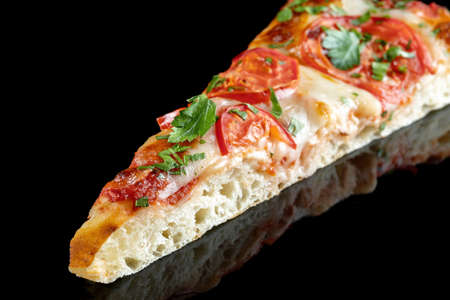 Slice of pizza with tomatoes and parsley, on a black mirrored background. Beautiful light, product reflection.の写真素材