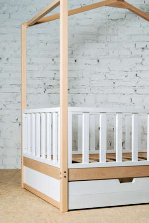 Childrens wooden bed in the form of a house on a background of a brick wall.の写真素材