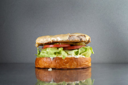 Burger with onions and mayonnaise, on a gray metal table. Junk food.の写真素材