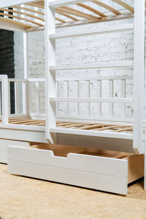 The image of the childs bed, bottom view of the storage drawers. White beautiful furniture, Vertical photo.の写真素材