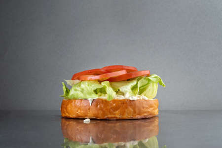 Burger with onions and mayonnaise, on a gray metal table. Junk food, delicious. Only tomatoes.の写真素材