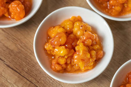 Juicy ripe cloudberry northern in a plate. Many plates on the table.