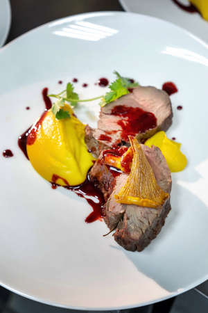 Beef cheek steak, caramelized in wine sauce with chanterelles in a white plate.