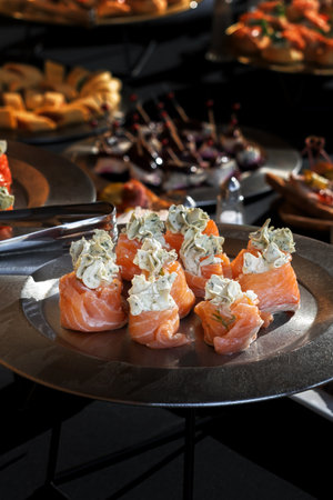Salmon rolls stuffed with dill cheese. A silvery dish, luxury catering, a richly laid table.の写真素材