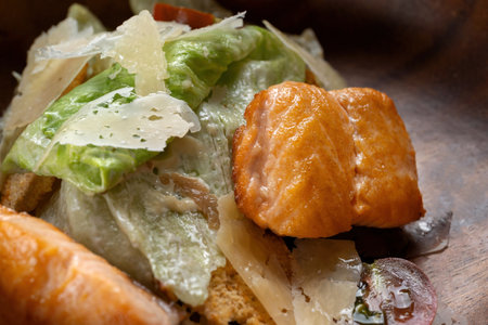 Caesar Salad with Grilled Salmon on wooden Plate Isolated. Salad with Red Fish Fillet, Mini Baguette Crackers.の写真素材