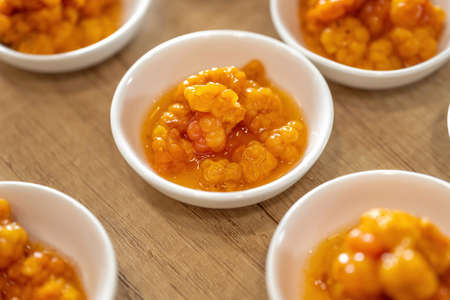 Juicy ripe cloudberry northern in a plate. Many plates on the table.の写真素材