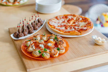 In the foreground salmon with cheese, and stuffed profiteroles. Balls of cream cheese. In the background pizza.の写真素材