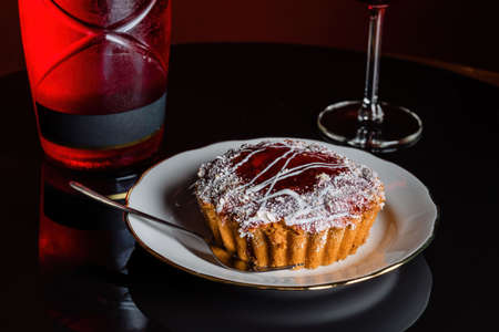 Glass of rose wine and beautiful cupcake with filling. Beautiful glazed cake sprinkled with powdered...