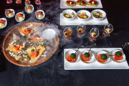 Catering, a table with dishes, a cup with liquid nitrogen, there is a beautiful smoke.の写真素材