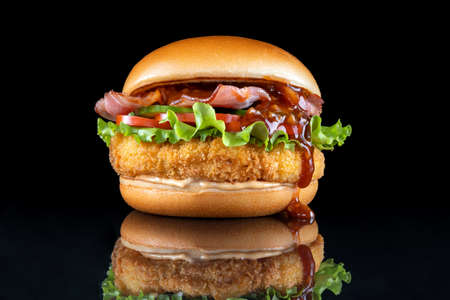 Bacon cheeseburger hamburger isolated on black. BBQ sauce and lettuce. The sauce flows nicely.の写真素材