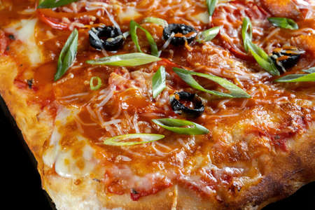 Pizza with cheese, olives and green onions. On a black isolated background.の写真素材