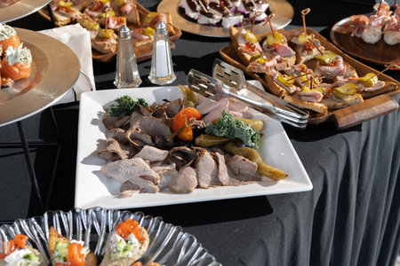 Meat snacks and pickles. Beautiful black tablecloth.の写真素材