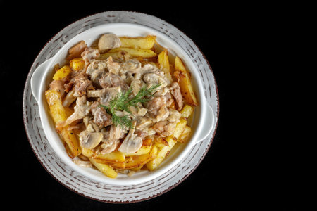 Rustic potatoes with meat and mushrooms. In a plate on a black background.の写真素材